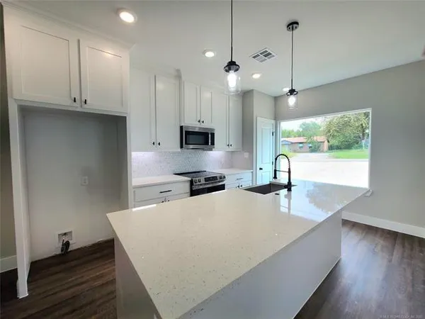a kitchen with kitchen island a counter space a sink appliances and cabinets