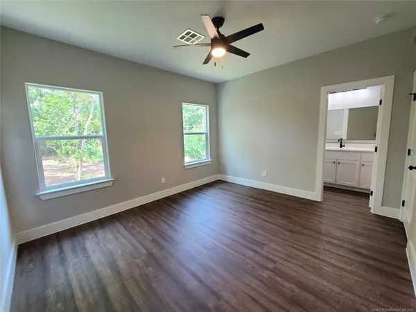 a view of empty room with wooden floor and fan