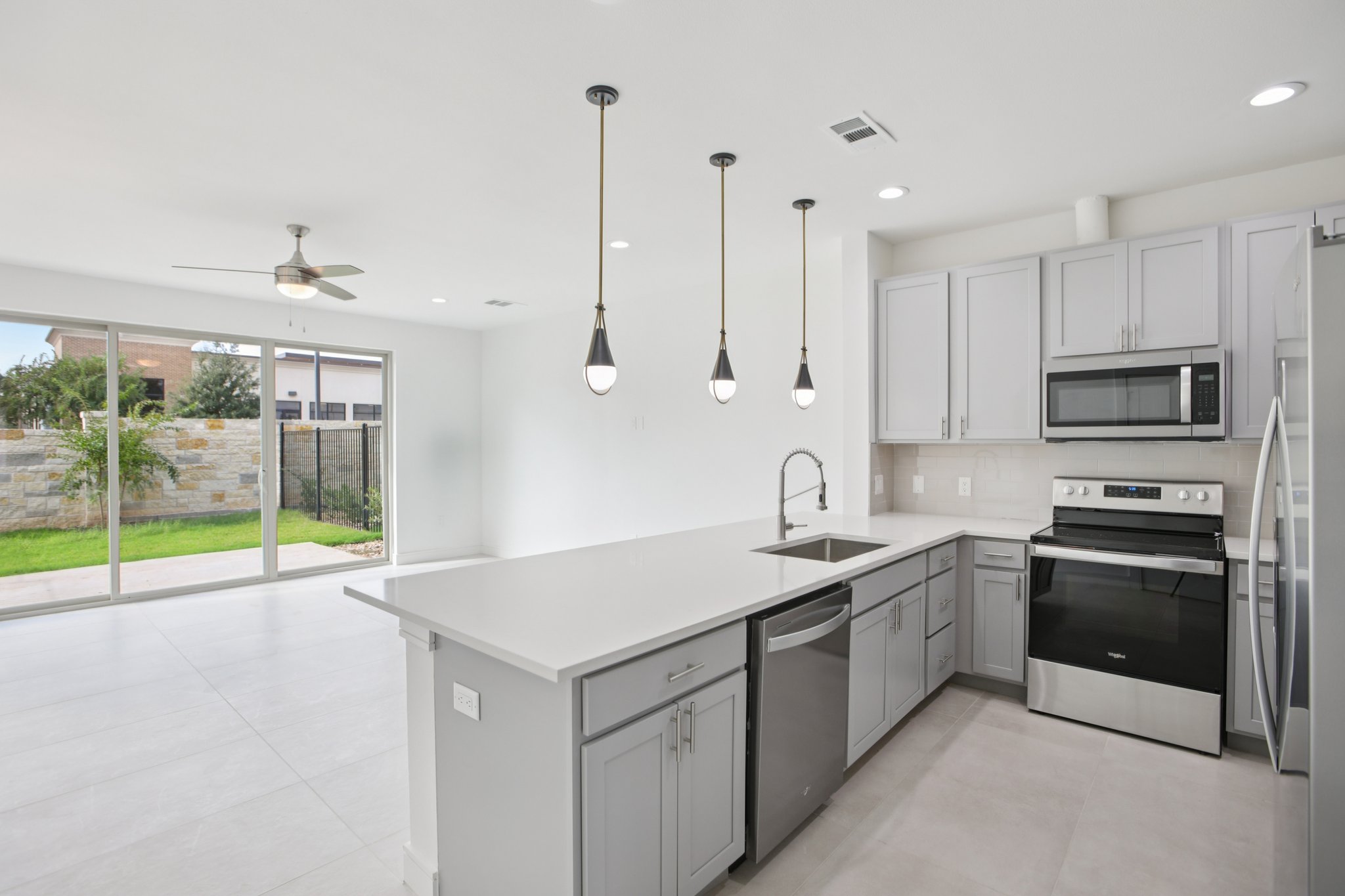 202 Tesla Circle Austin, TX 78681 - Photo 11 of 35 Kitchen with stainless steel appliances, gray cabinets, a peninsula, tasteful backsplash, and light stone countertops