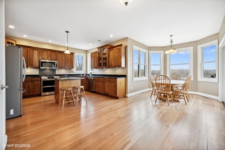41-w580 McDonald Road Elgin, IL 60124 - Photo 8 of 25 a open kitchen with stainless steel appliances granite countertop a stove top oven a dining table and chairs with wooden floor