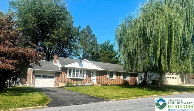 a view of a white house with a big yard and large trees