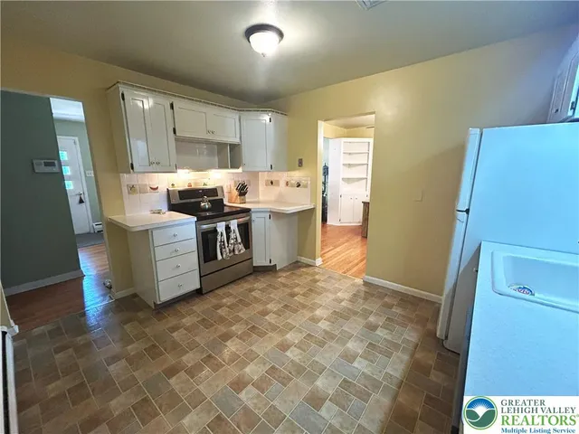 a kitchen with stainless steel appliances a stove a refrigerator a sink a counter top space and cabinets