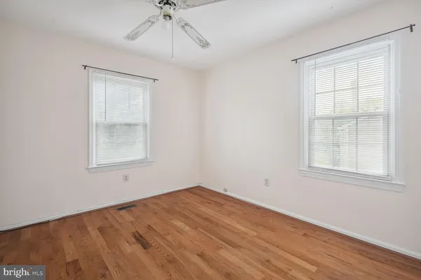an empty room with a chandelier fan and windows
