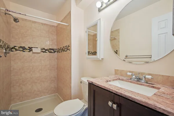a bathroom with a granite countertop sink toilet mirror and shower