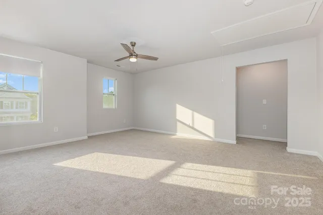 an empty room with windows and ceiling fan