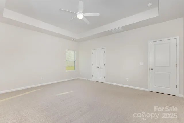 an empty room with windows and fan