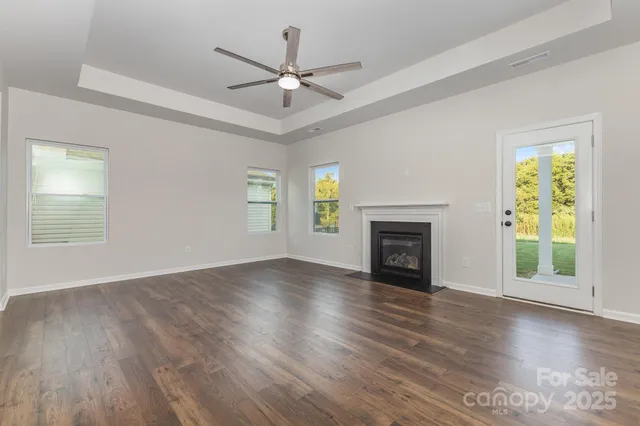 a view of an empty room with wooden floor fireplace and a window