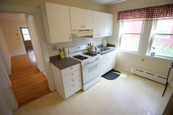 a kitchen with white cabinets and window