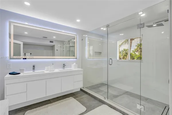 a bathroom with a double vanity sink mirror and shower