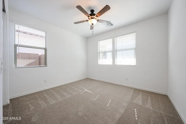 an empty room with windows and ceiling fan