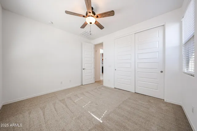an empty room with closet and ceiling fan
