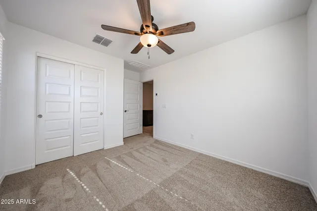 an empty room with a ceiling fan and closet
