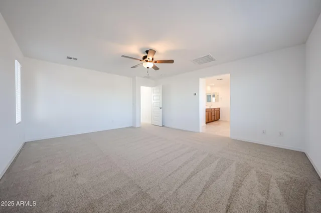 a view of an empty room with a chandelier fan
