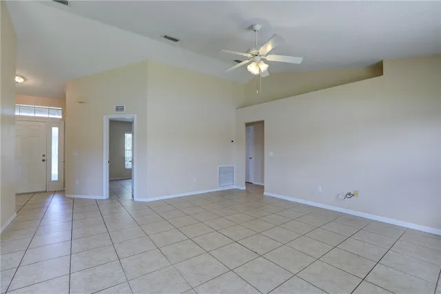a view of an empty room and chandelier fan