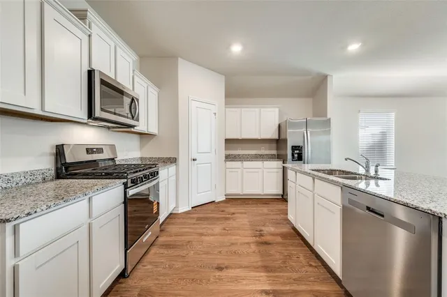 a kitchen with stainless steel appliances granite countertop a stove a sink and a refrigerator