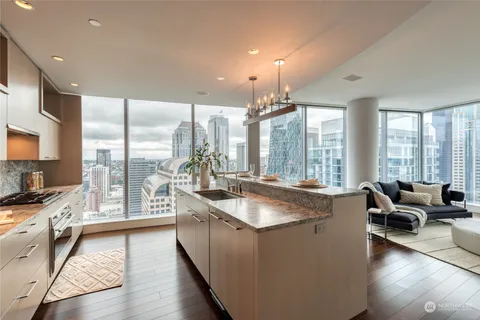 a large kitchen with kitchen island a large window cabinets a sink and stainless steel appliances