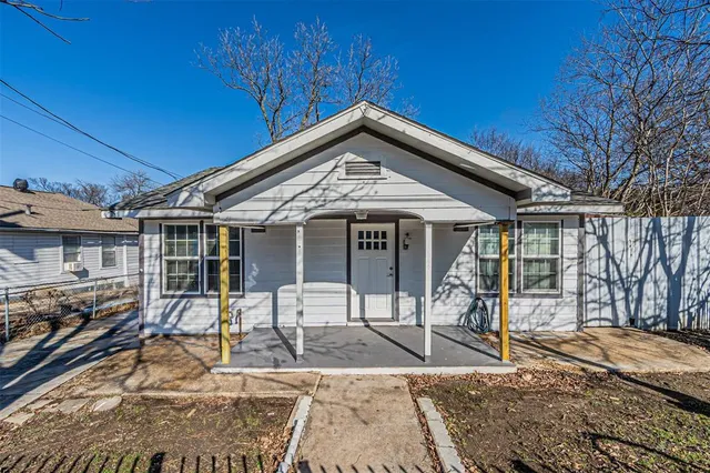 a patio with a table and chairs and potted plants