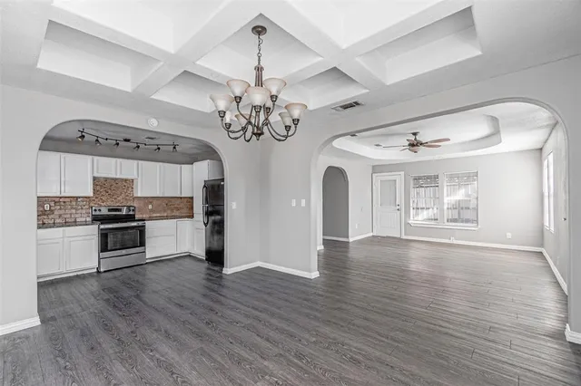 a large kitchen with stainless steel appliances granite countertop a stove oven a sink dishwasher and white cabinets with wooden floor