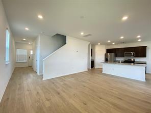 213 Saide Street Georgetown, TX 78626 - Photo 7 of 32 Light wood-finish flooring extending through an open-concept space, featuring recessed lighting, a modern kitchen island with an integrated sink, dark wood cabinetry, and stainless steel appliances