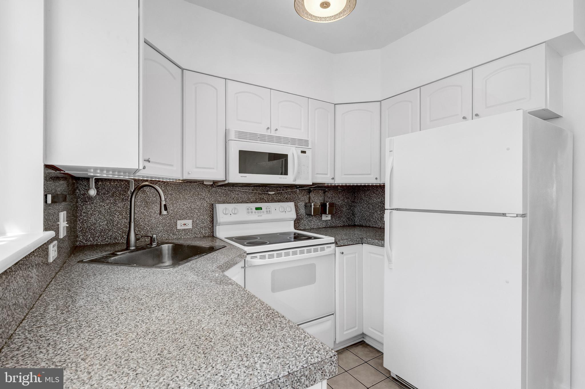 1749 L Street Northeast Washington, DC 20002 - Photo 10 of 24 a kitchen with stainless steel appliances granite countertop a refrigerator stove a sink and a microwave