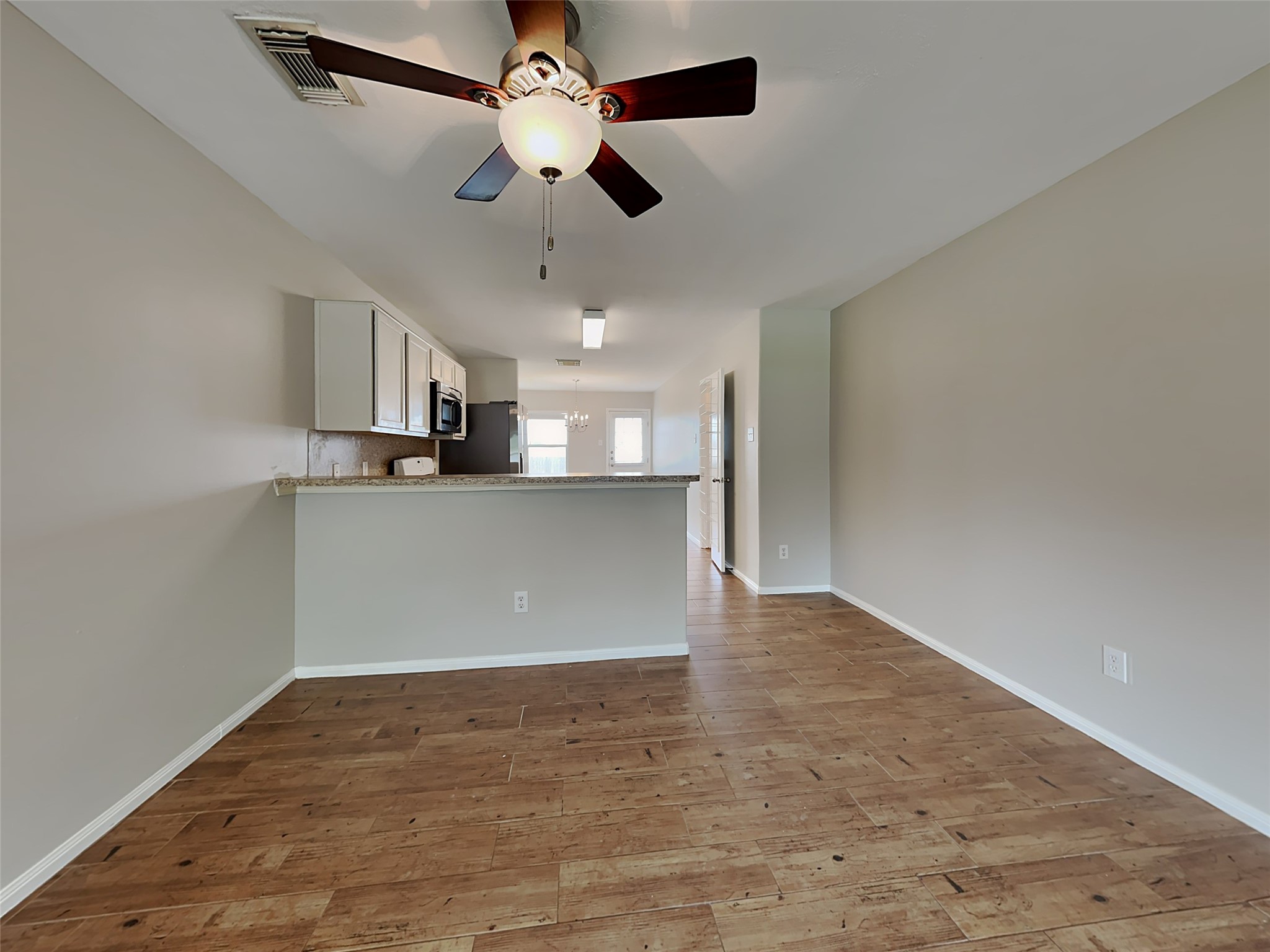 8119 Katie Mill Trail Spring, TX 77379 - Photo 11 of 18 an empty room with wooden floor a ceiling fan and kitchen view
