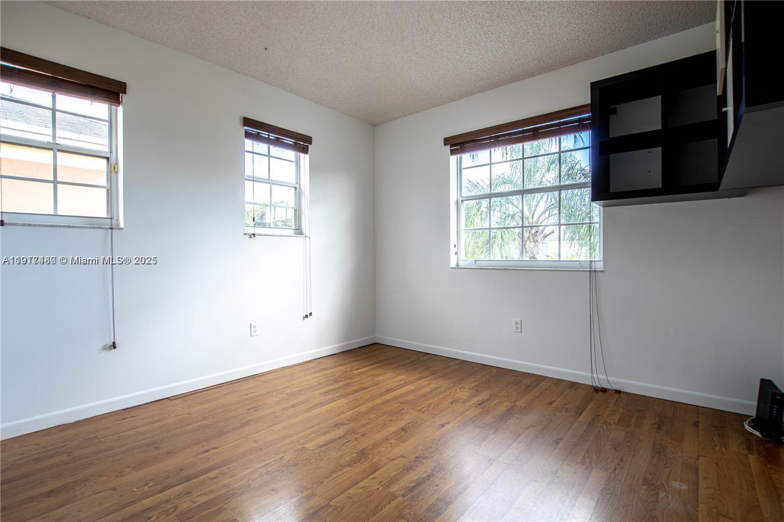 16227 Southwest 139th Court, Unit 2 Miami, FL 33177 - Photo 7 of 10 an empty room with wooden floor and windows