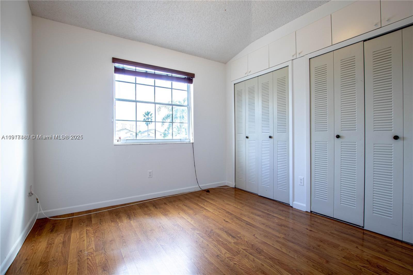 16227 Southwest 139th Court, Unit 2 Miami, FL 33177 - Photo 8 of 10 an empty room with wooden floor and windows