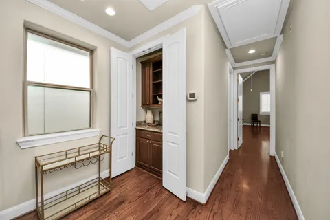 a view of a hallway to a livingroom with wooden floor and furniture