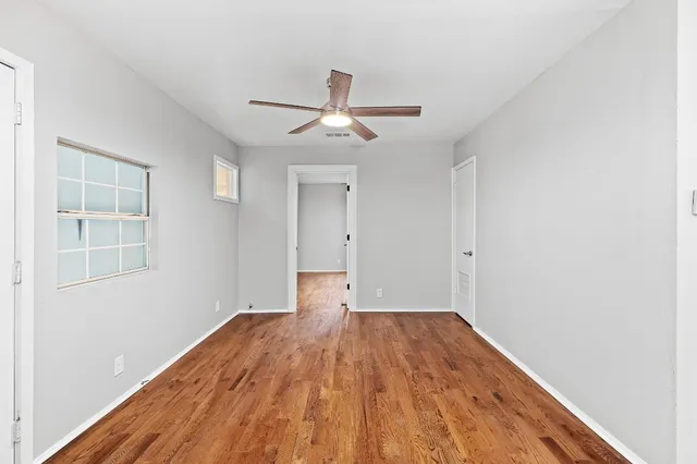 a view of empty room with wooden floor and fan