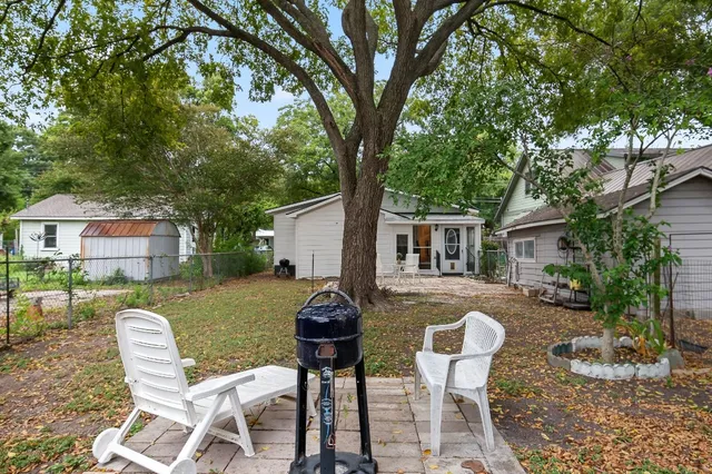 a view of a backyard with table and chairs potted plants and large tree