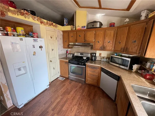 a kitchen with stainless steel appliances a refrigerator a sink and wooden floors