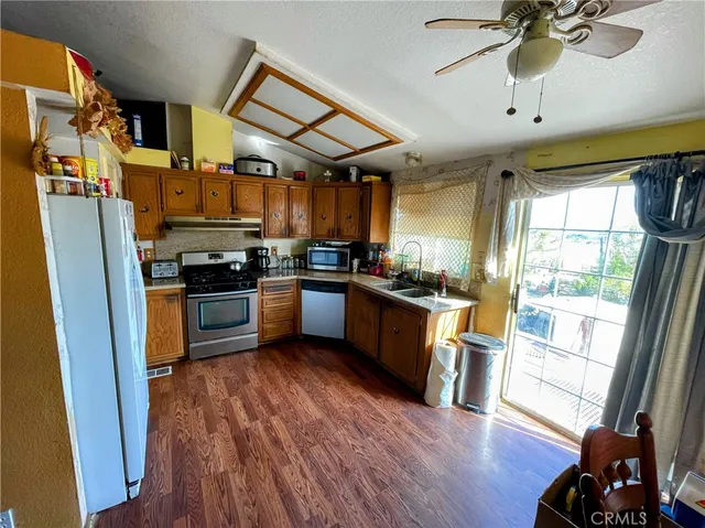 a kitchen with stainless steel appliances a stove a sink a refrigerator cabinets and wooden floor