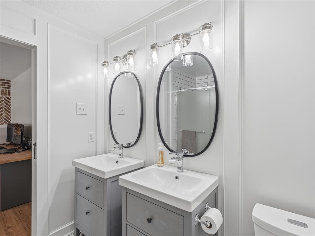 12724 Carpenter Lane Rhome, TX 76078 - Photo 16 of 37 Dual vanity featuring integrated sinks, gray shaker-style cabinetry, and oval mirrors with black frames