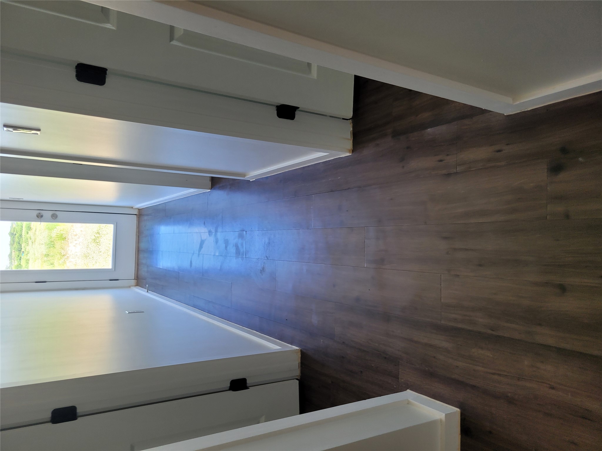 422 A Road Stockdale, TX 78160 - Photo 22 of 40 A well-lit hallway with rich wood-look flooring leads to an outdoor view.