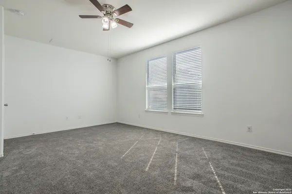 an empty room with windows and fan