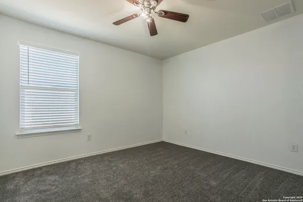 an empty room with a window and a fan