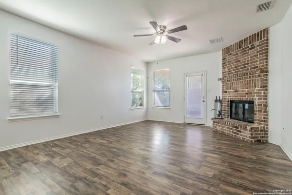 an empty room with windows fireplace and wooden floor