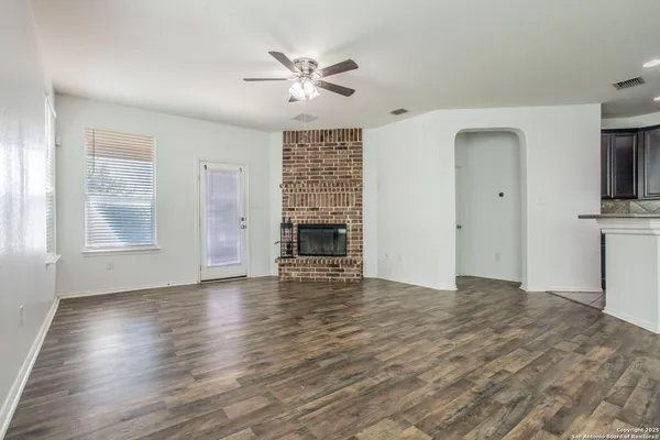 an empty room with wooden floor fireplace and windows
