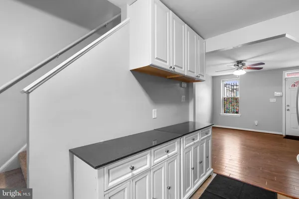 a kitchen with granite countertop white cabinets and wooden floor