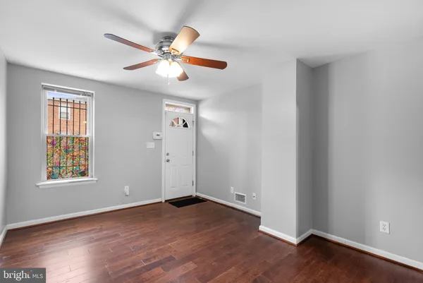 an empty room with wooden floor fan and windows