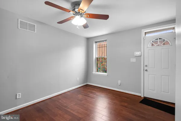 an empty room with wooden floor chandelier fan and windows