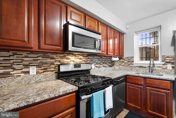 a kitchen with granite countertop stainless steel appliances a stove sink and cabinets
