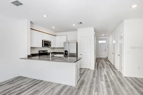 a large kitchen with stainless steel appliances a large counter top a stove and a refrigerator