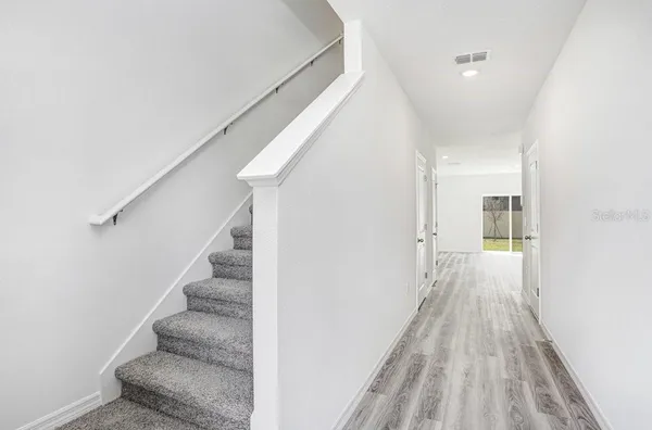 a view of a hallway with wooden floor and staircase