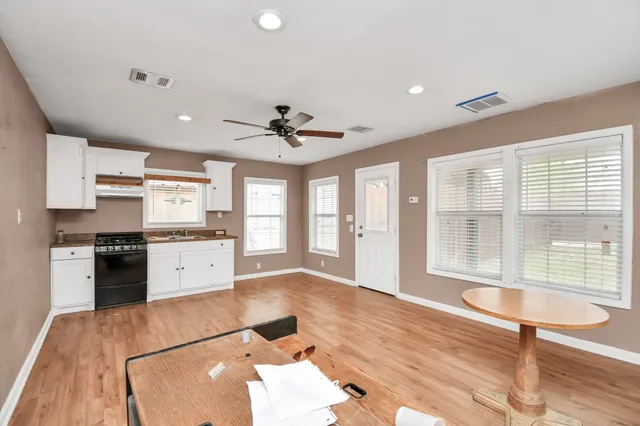 a kitchen with granite countertop a stove a sink and white cabinets with wooden floor