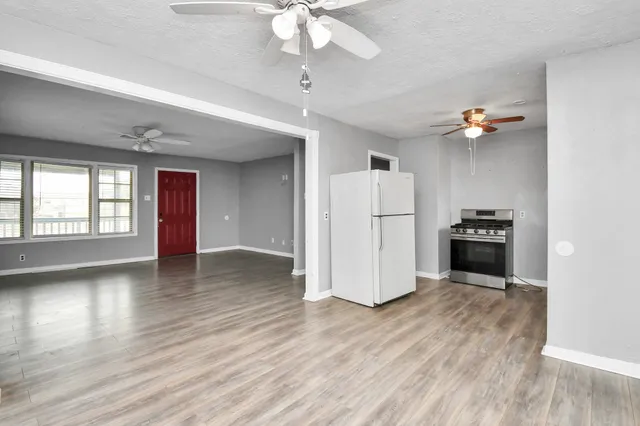 a view of a kitchen with a refrigerator a ceiling fan and wooden floor
