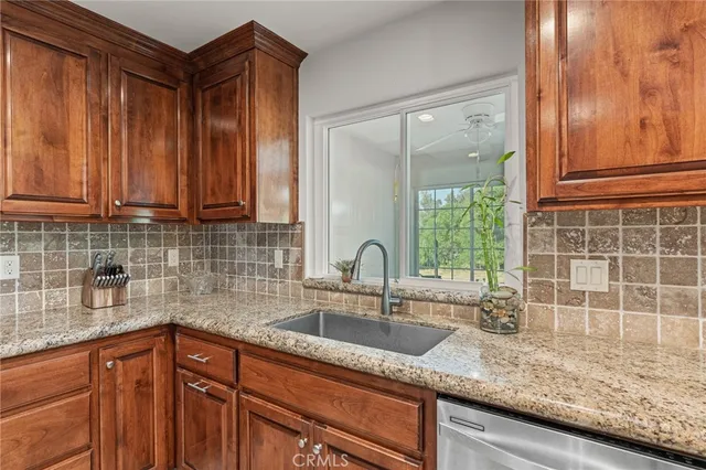a kitchen with granite countertop a sink and a wooden cabinets