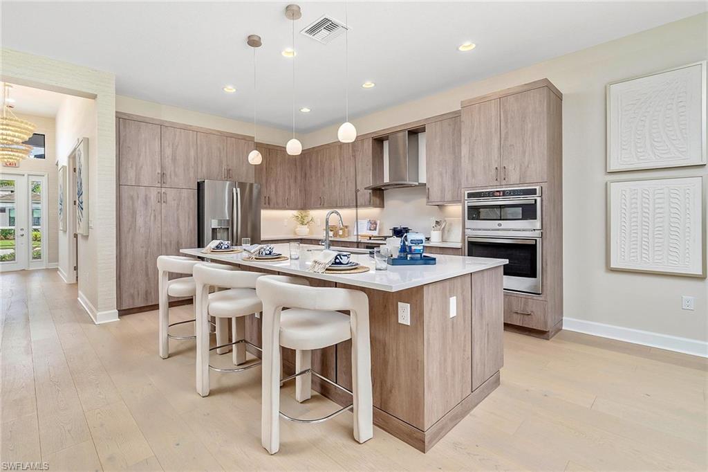 12777 Springbrook Court Estero, FL 33928 - Photo 2 of 27 a kitchen with kitchen island granite countertop wooden cabinets and refrigerator