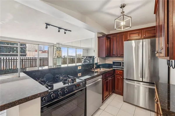 a kitchen with stainless steel appliances granite countertop a stove a refrigerator and a sink with wooden cabinets