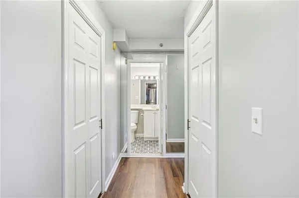 a view of a hallway with wooden floor and a bathroom